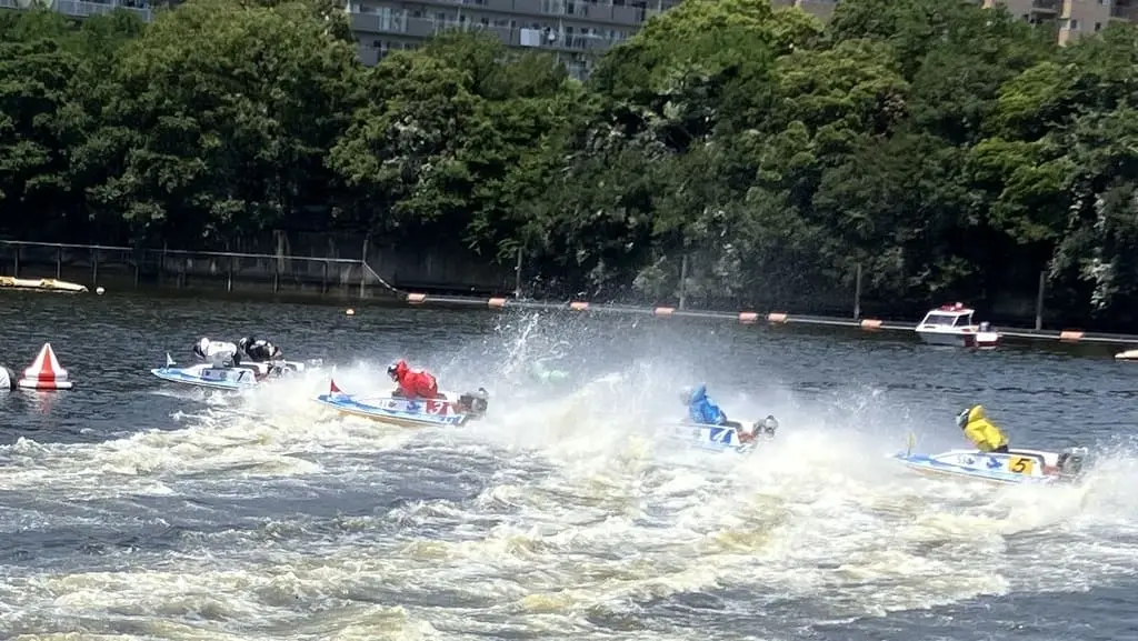 Six boats racing at full speed during a kyotei (boat race) at BOAT RACE Heiwajima, with splashing water and vivid rider colors.